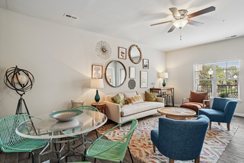 a living room with a ceiling fan and a round glass table